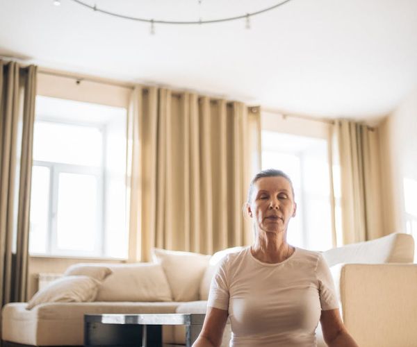Person sitting comfortably on a yoga mat in a calm setting.